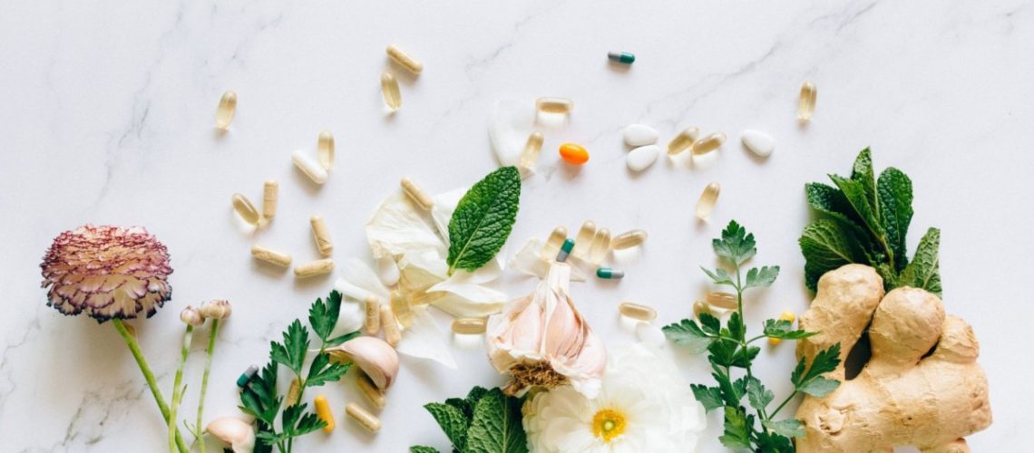 vitamins, herbs and foliage, flowers on marble background