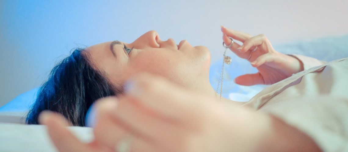 women lying down pensive, playing with one necklace in her fingers looking at the ceiling